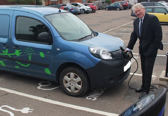 Man in suit charging an electric vehicle