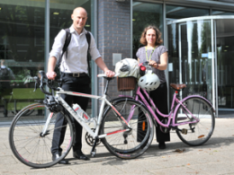 Two cyclists with bicycles outside the front of a business building